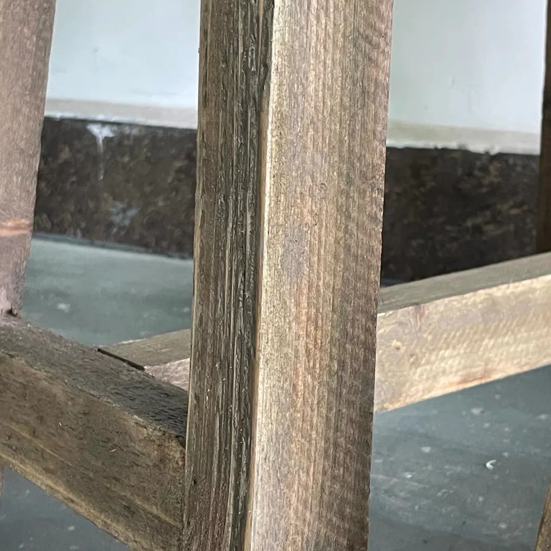 Close-up of a rustic fir wood stool leg and stretcher showing the wood grain