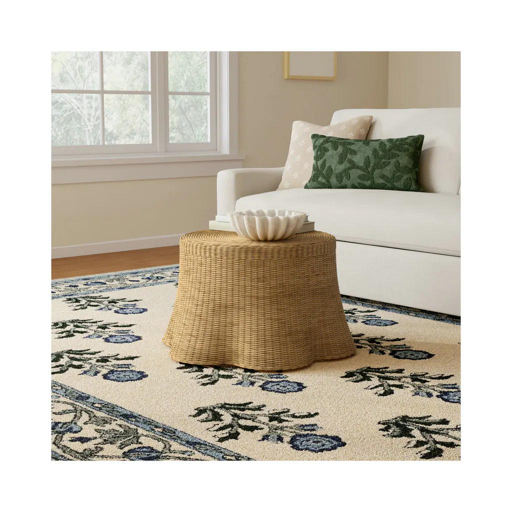 Round woven rattan coffee table on a patterned rug beside a white sofa
